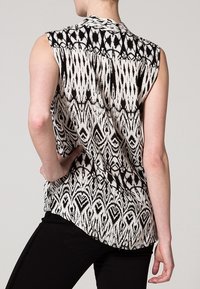 Bezramkowy, czarno-biała wzorzysta bluzka z wysokim dekoltem, z abstrakcyjnym wzorem i zaokrąglonym hemem z tyłu.