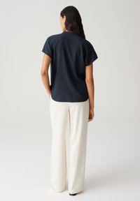 Top corto texture navy a maniche corte abbinato a pantaloni larghi color crema; design semplice con vestibilità rilassata e un sottile dettaglio all'orlo.