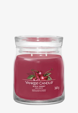 Glazen potkaars met dieprode was, gelabeld "Yankee Candle Black Cherry," met kersen afgebeeld en een gewicht van 368 gram.