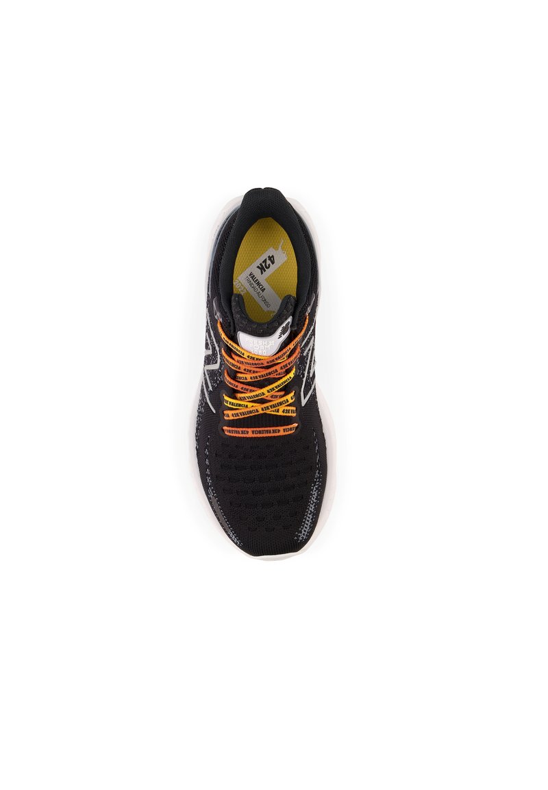 Zapatilla deportiva negra con parte superior de malla texturizada, cordones vibrantes en naranja y una entresuela blanca acolchada, con un logo prominente en el costado.