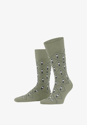 Olivgrüne Socken mit einem Rautenmuster in Marineblau und Weiß, die kleine Bleistiftzeichnungen zeigen. Stricktextur mit einem gerippten Bund.