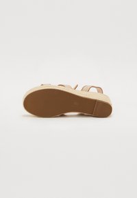 Sandale cu toc wedge, cu un upper sintetic de nuanță bronz, talpă espadrile texturată și fund din cauciuc. Dispune de două bretele ajustabile pentru o fixare sigură.