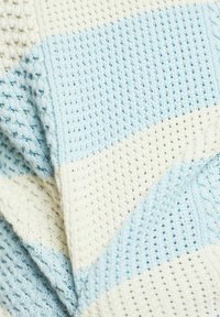 Strickdecke mit hellblauen und cremefarbenen Streifen, strukturierten Mustern und einem weichen, atmungsaktiven Stoff mit gewebtem Design.