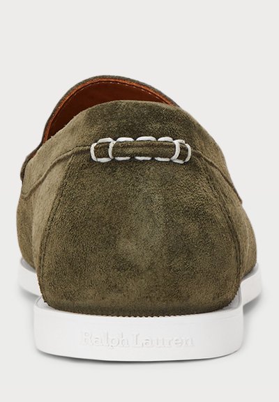 Green suede slip-on shoe with white rubber sole, featuring a decorative stitched loop detail at the heel and embossed brand name.