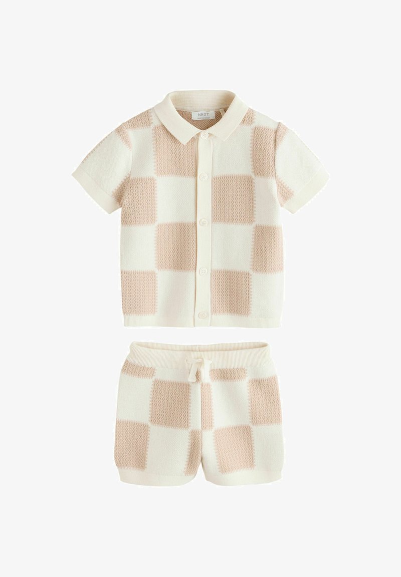 Ensemble tricoté à manches courtes avec col, couleur crème avec motif à blocs pêche clair. Comprend un haut boutonné et un short assorti à taille élastique.