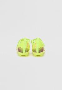 Lyse neon gule fotballsko med teksturert design, mesh-overdel, lilla striper og bakre trekkremmer for enkel påkledning.