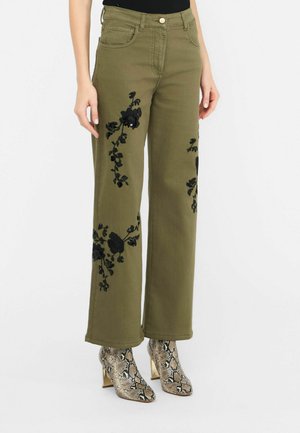 Olijfgroene wijde broek met zwarte bloemenborduursels aan de voorkant. Gemaakt in combinatie met gestructureerde slangenprint enkellaarsjes.