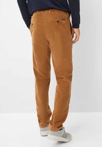Corduroy broek in een warme bruine kleur, met een gestructureerd oppervlak, twee achterzakken met knopen en een getailleerde pasvorm.