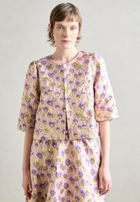 Blomsterbrodert jakke i rosa med grønne og lilla blomster mønstre. Korte ermer, teksturert stoff og en crop design.