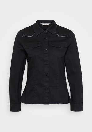 Svart denimskjorte med lange ermer, spiss krage og to brystlommer. Har sølvnagler på skuldrene og knapper foran.