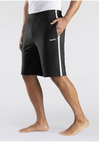 Black athletic shorts with a white side stripe, elastic waistband, and logo on the front. Made from a smooth fabric, knee-length design.
