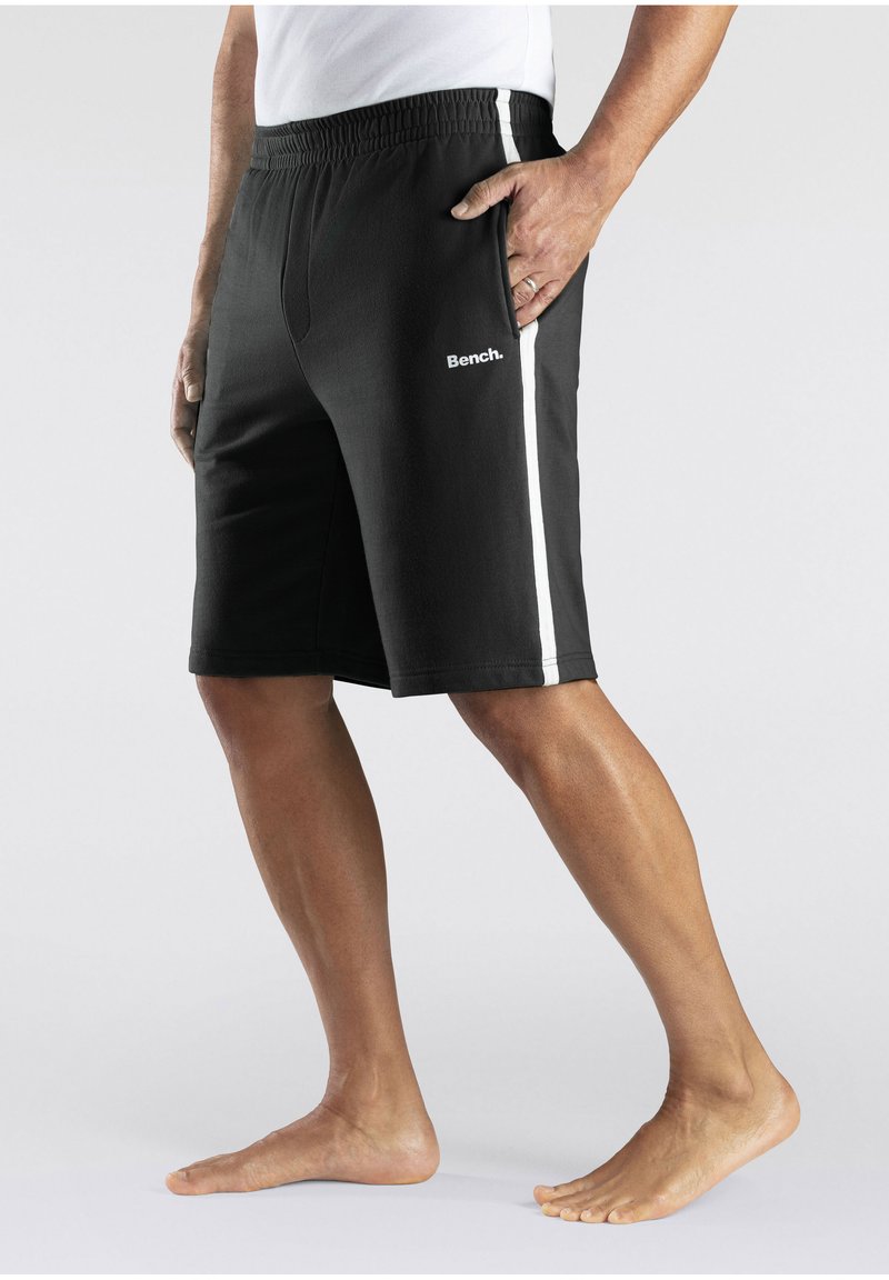 Black athletic shorts with a white side stripe, elastic waistband, and logo on the front. Made from a smooth fabric, knee-length design.