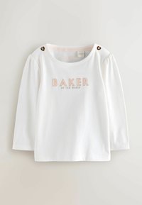 Valkoinen pitkähihaisaita, jossa on pullistuneet hihat ja kevyesti vaaleanpunaisen "BAKER"-logon brodeeraus. Yksityiskohtana sydämenmuotoinen nappi olkasaumassa.