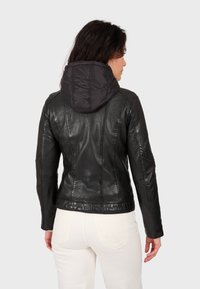 Čierna kožená bunda s prešívanou, odnímateľnou kapucňou a prispôsobeným strihom. Textúrovaný povrch a bezšvové detaily na zadnej strane.