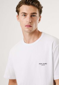 Balta medvilninė marškinėliai su apvali kaklo iškirpte ir trumpomis rankovėmis. Mažas juodas "Pepe Jeans London" logotipas kairėje krūtinės pusėje.