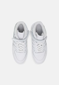 Zapatillas altas de cuero blanco con puntera perforada y acentos en azul claro, que cuentan con cierre de cordones y correa ajustable.