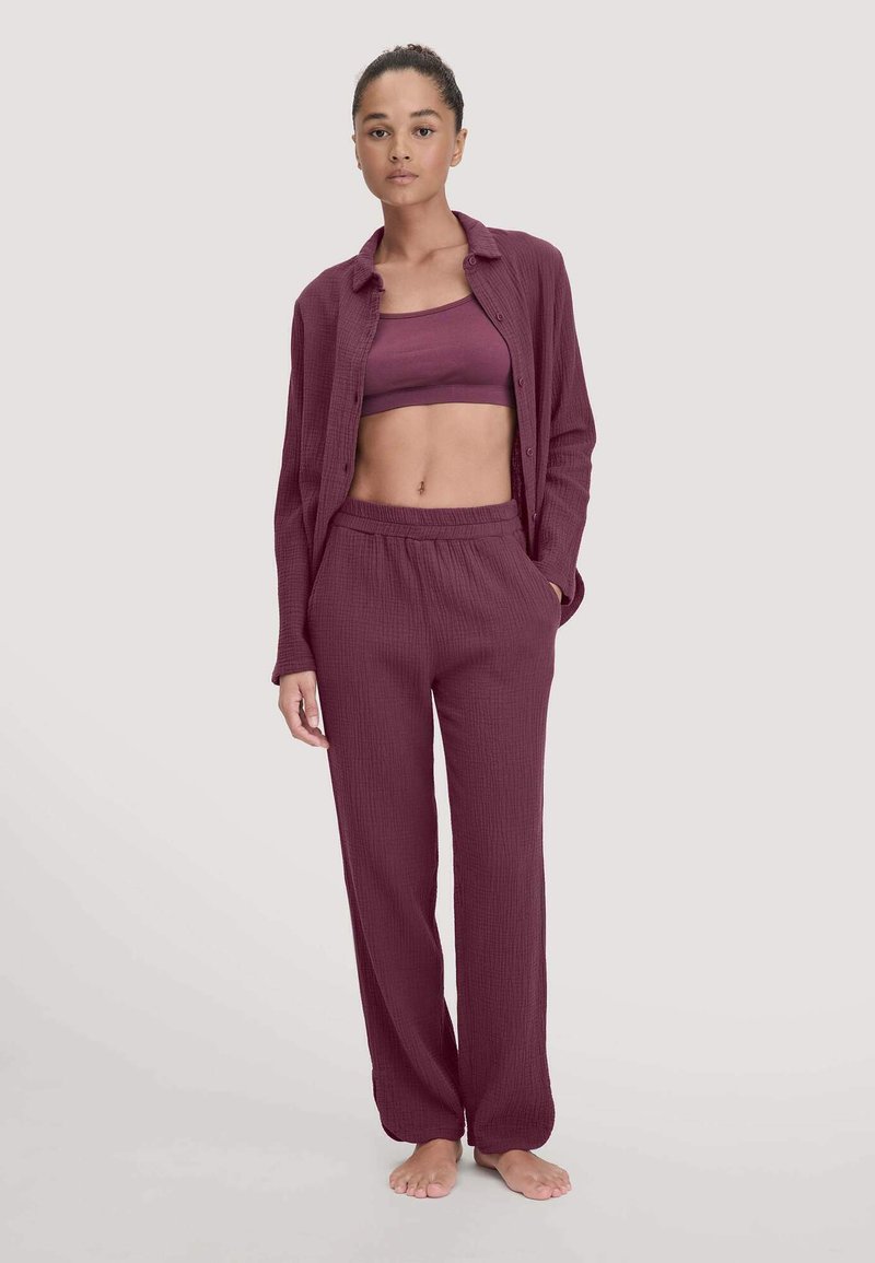 Burgunderfarbene Loungewear-Set mit einem strukturierten offenen Knopfhemd, passenden Hosen mit elastischem Bund und einem figurbetonten Crop-Top.