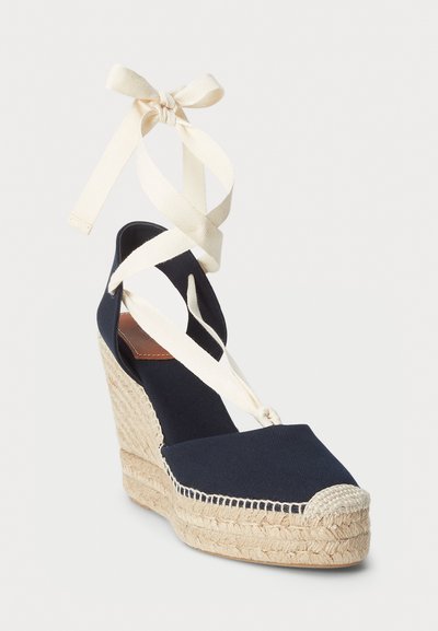 Tumesinine kanvasest ehted espadrillid beeži paelaga, punutud jute talla ja ümmarguse varbaga, millel on kontrastne beež kapsel detail.