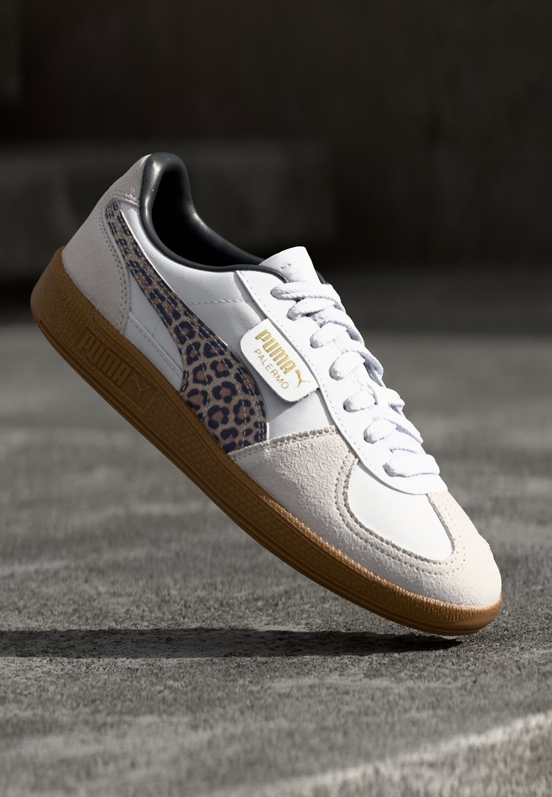 Baskets blanches avec des accents en daim et en cuir. Présentent un panneau latéral en imprimé léopard, un col rembourré et une semelle en caoutchouc texturée. Détail en logo doré.