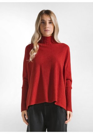 Roter Strickpullover mit langen Ärmeln, hohem Rippenkragen und gerippten Bündchen. Weiche Textur; lockere Passform mit Seitenschlitzen am Saum.