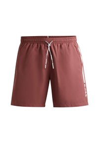 Røde badebukser lavet af et glat stof. Har en elastisk talje med snor og hvide logo-detaljer på siden.