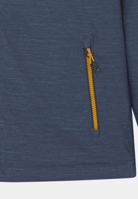 Marineblaue Jacke aus strukturiertem Stoff, mit einem Reißverschlussfach in Gelb und einer glatten Oberfläche. Keine weiteren Details sichtbar.