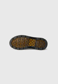 Rubber shoe sole with rectangular tread patterns, textured edges, and transparent amber details on a white background.