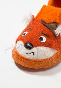 Lysorange filttofflor med en rävansiktsdesign, svarta ögon detaljer, vit nos och en liten brun hatt som accent. Mjuk textur.