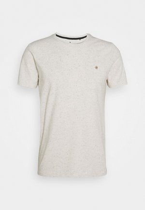 T-shirt beige clair en tissu texturé, avec un col rond, des manches courtes et une poche poitrine avec un détail en bouton.