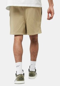 Pantaloni corti beige con una vestibilità comoda, tessuto liscio e design semplice. Indossati con calzini bianchi a girocollo e scarpe da ginnastica grigie e nere.