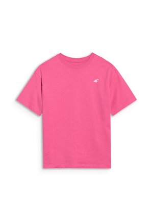 Dziewczyna idąca w czarnych trampkach, białych skarpetkach, beżowych szortach, różowym oversize t-shircie i szarej czapce noszonej tyłem na jednolitym tle.