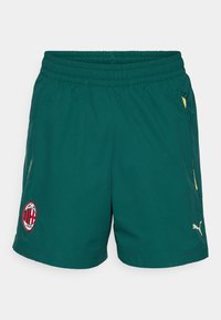 Zielone spodenki sportowe wykonane z lekkiego materiału, z elastycznym pasem na sznurek, bocznymi kieszeniami, żółtymi akcentami i czerwonym logo.