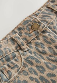 Leopardskönt denim med en beige bas och blå accenter, med framträdande sömmar, en metallknapp och en framsidig ficka.