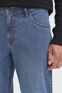 Blugi din denim albastru deschis, cu croială dreaptă, cusături vizibile, buzunare frontale și închidere cu nasture la talie.