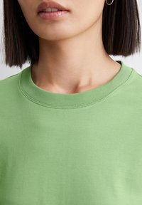 Groene katoenen sweatshirt met een ronde halslijn, voorzien van een gladde textuur en geribbeld afwerkdetail langs de kraag voor extra flair.