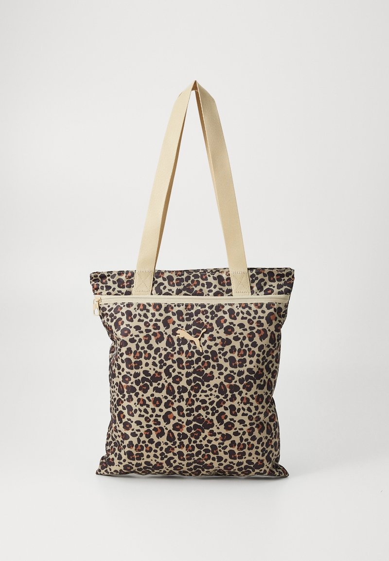 Sac cabas imprimé léopard avec fermeture éclair beige et longues anses assorties sur fond blanc uni.