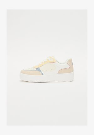 Sneaker blanche avec des accents pastel en jaune, rose et bleu. Matériaux en cuir lisse et en daim. Semelle en caoutchouc blanc épais avec un grip texturé.