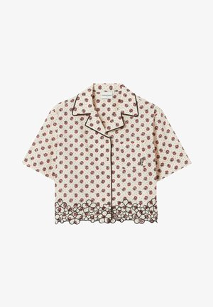 Blouse crème à manches courtes avec petit imprimé floral rouge, col noir à passepoil, fermeture boutonnée devant, poche poitrine et ourlet en dentelle florale festonnée.