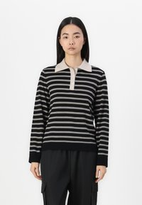 Polo a maniche lunghe a righe nere e beige con colletto e patta dei bottoni, realizzato in un morbido tessuto testurizzato.