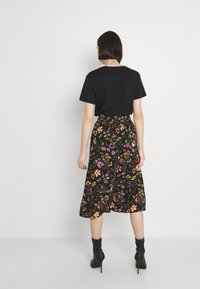 Black short-sleeve t-shirt paired with a black floral midi skirt featuring multicolor flowers, worn with black high-heeled boots.