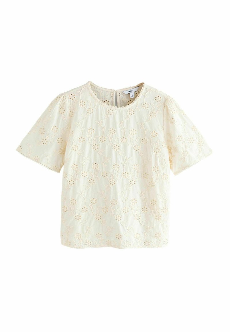 Blusa corta a maniche corte in crema chiaro con ricami floreali e scollatura ondulata. Tessuto testurizzato con delicati dettagli in pizzo.