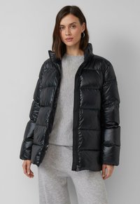 Melna pūkaina jaka ar rāvējslēdzēju priekšā, ar augstu apkakli, kvadrātveida stiprinājumiem un gludu, spīdīgu tekstūru. Apvienota ar pelēku augšdaļu.