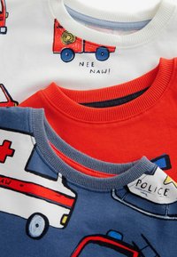 Tre kortärmade t-shirts i vitt, rött och blått. Har tryckta motiv av utryckningsfordon, med ribbad rund halsringning.