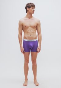 Μωβ ανδρικά εσώρουχα τύπου boxer με λευκή μέση που φέρει την επιγραφή «POLO RALPH LAUREN», κατασκευασμένα από μαλακό, ελαστικό υλικό, στενή εφαρμογή και μήκος μέχρι τη μέση του μηρού.