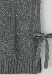 Pull griss tricoté avec un motif texturé, présentant un détail de ruban noué sur le côté et un ourlet côtelé en bas.