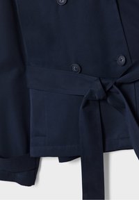 Navy blue double-breasted jacket with large buttons, a tied waist belt, and a smooth texture. Features a slight sheen and tailored fit.