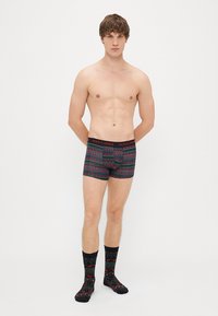 Fekete boxer alsónadrág mintás dizájnnal piros és zöld színben. Kiemelt derékbőség "JACK & JONES" felirattal. A modellen illeszkedő zoknik vannak.