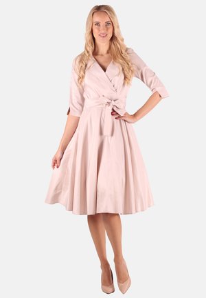 Helles rosa Wickelkleid mit einem Bindegürtel, drei Viertelärmeln und einem ausgestellt Rock. Glattes Material mit leichtem Glanz.