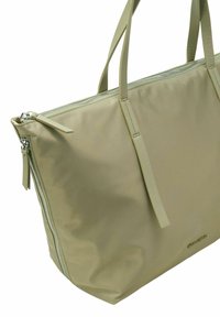 Grand sac fourre-tout en nylon khaki doux avec une fermeture éclair argentée contrastante et de longues anses plates. Dispose d'une poche zippée extérieure sur le côté.