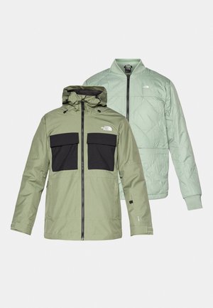 Δύο τζάκετ που επικαλύπτονται: ένα αδιάβροχο τζάκετ ελιάς με μαύρες τσέπες στο στήθος και κουκούλα, και ένα ελαφρύ τζάκετ μπομπούρ σε ανοιχτό μέντα χρώμα με επένδυση.